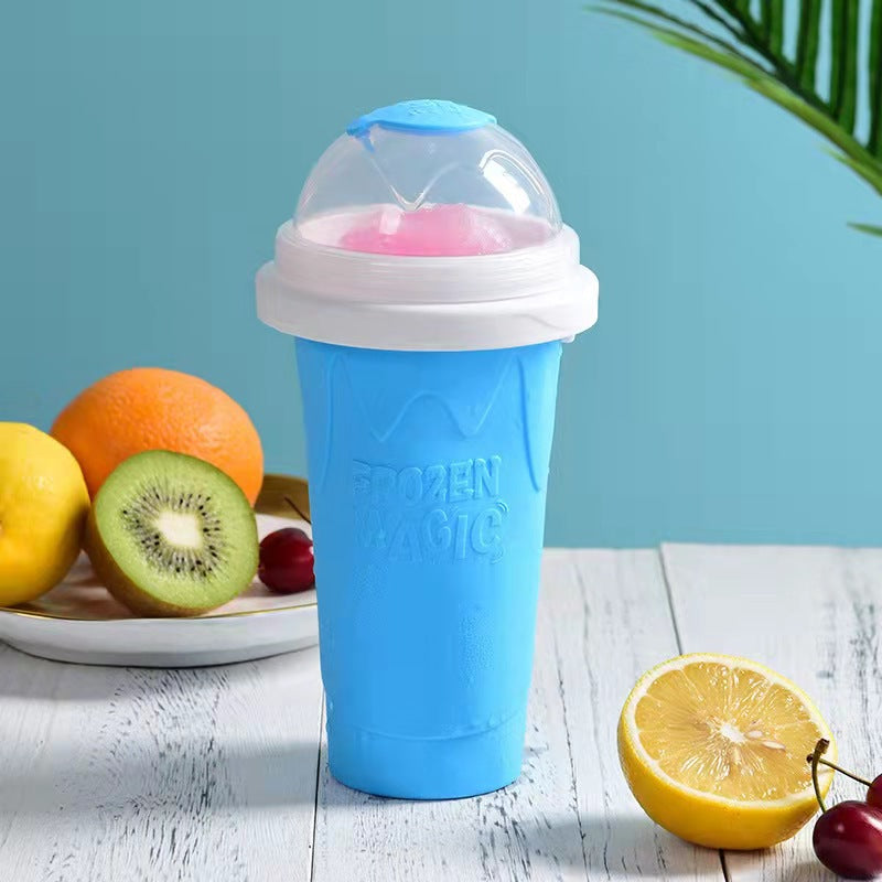 Blue slushy maker cup with pink ice cream on a wooden surface with fruits in the background