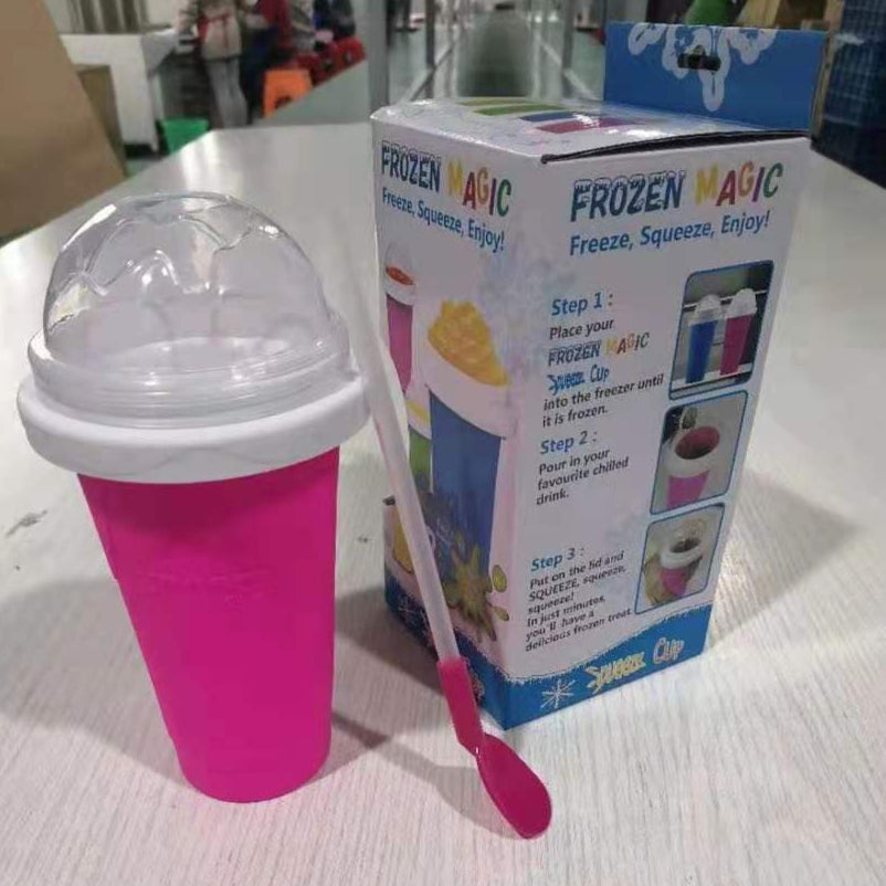 Pink sippy cup with a spoon next to its packaging on a white surface