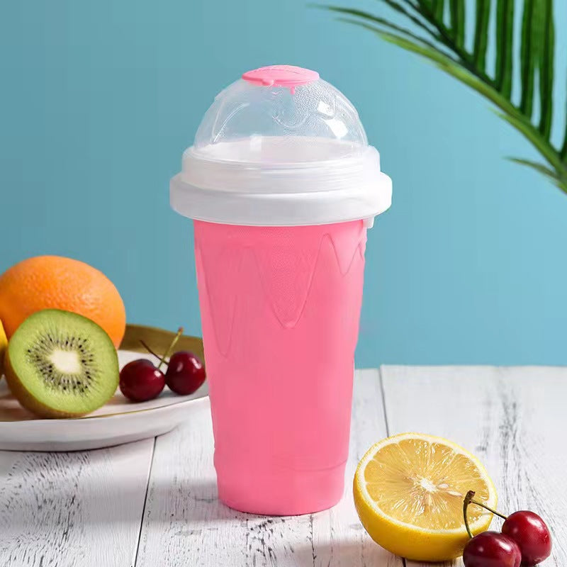 Pink silicone slushy maker cup with lid on a table with fruits