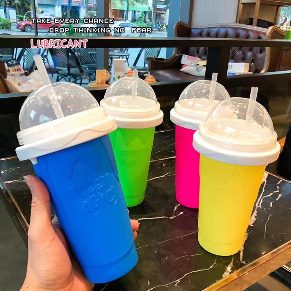 Colorful slushy maker cups with lids held by a hand on a table in a cafe.
